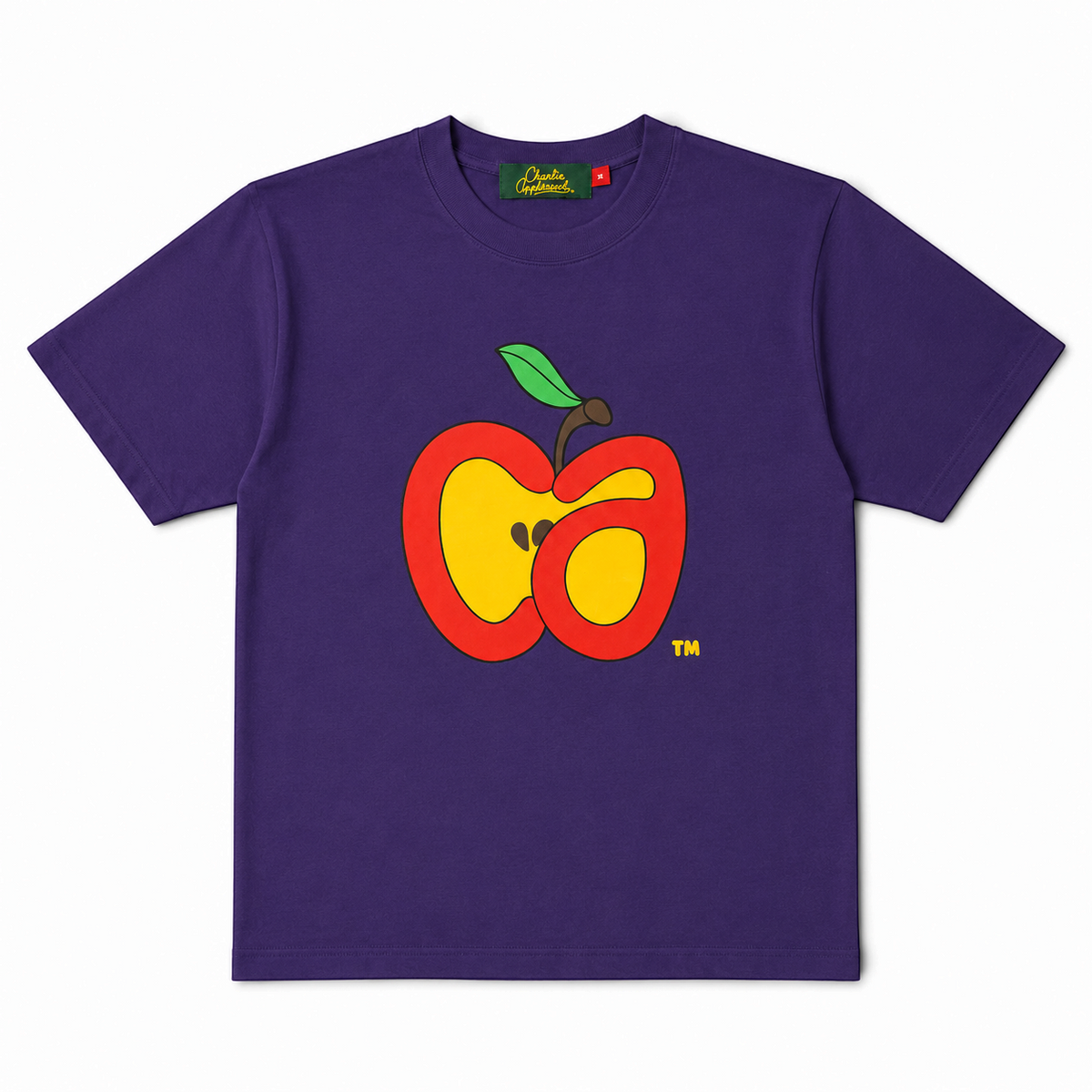 A purple short-sleeve t-shirt with a  graphic of a cut apple on the chest, featuring red, yellow, and green colors. The brand 'Charlie Appleseed' is visible on the inner neck label.